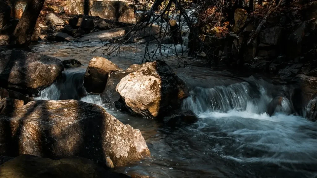 River flowing smoothly around rocks, symbolizing wu wei effortless action and flow