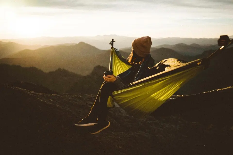 Solo hiker with simple, earth-toned minimalist hiking gear in quiet wilderness, embodying invisible design philosophy