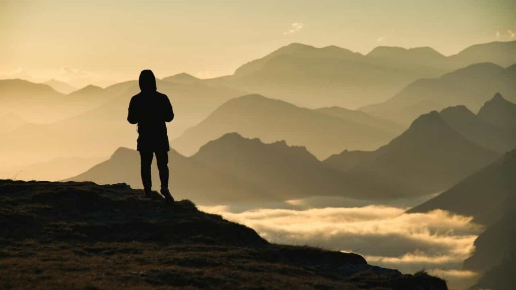 Hiker on a windy mountain ridge at sunset, caught between active-climb heat and cold stillness, embodying thermoregulation for hiking