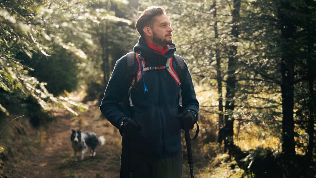 fleece midlayer for hiking - A hiker in a fleece jacket on a mountain trail in autumn, golden leaves on the ground, the fleece soft and warm against the cool air, the midlayer doing its work without drawing attention