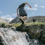 hiking shorts - A hiker in shorts and hiking boots crossing a stream on a summer trail